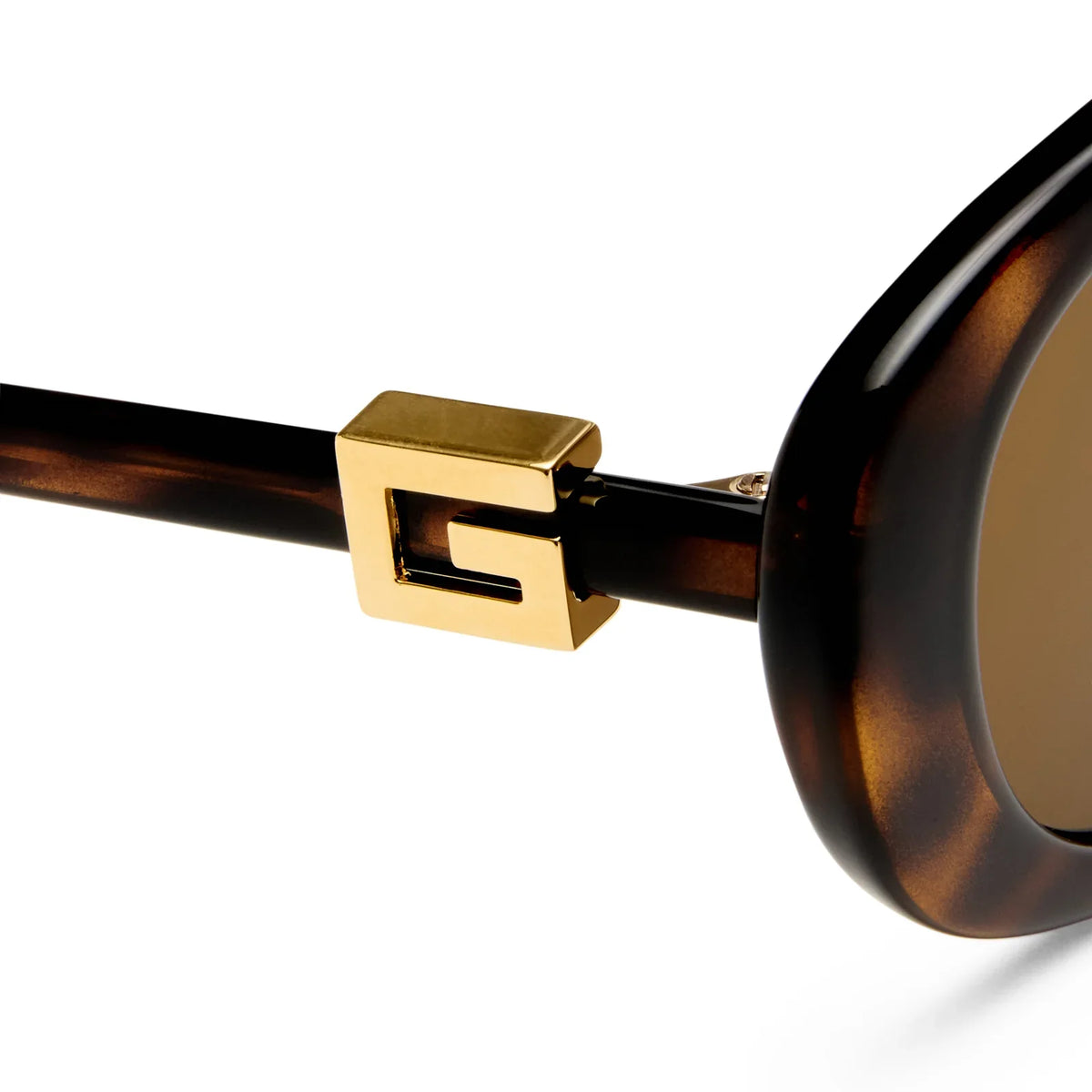 Close-up of brown tortoiseshell luxury sunglasses with a gold G-shaped temple detail.
