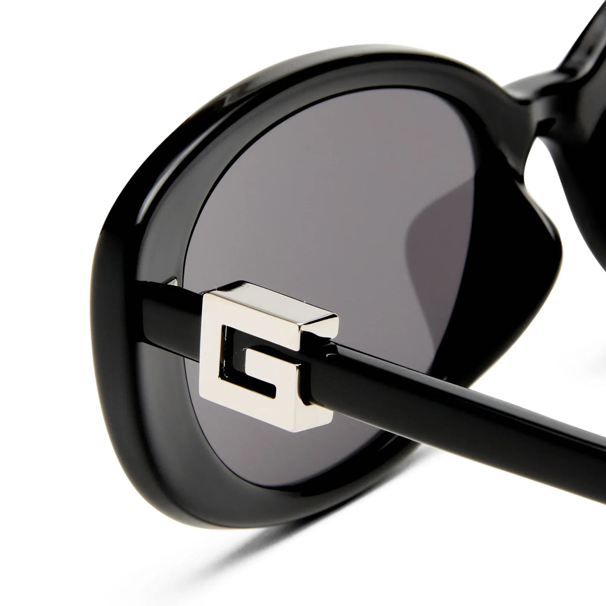 Close-up of black luxury sunglasses with a silver metallic G emblem on the temple.