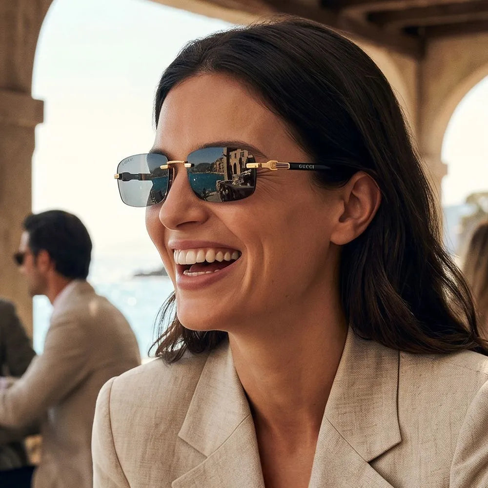 Smiling woman wearing luxury gold-framed Gucci sunglasses and a beige blazer.