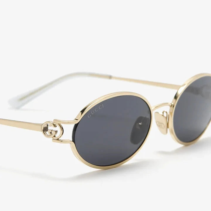 Gold-rimmed Gucci oval sunglasses with dark lenses and logo detail