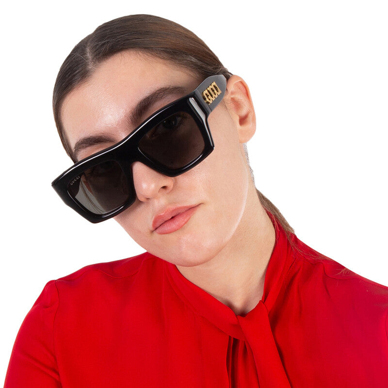 Woman wearing oversized black luxury sunglasses and a red silk blouse.