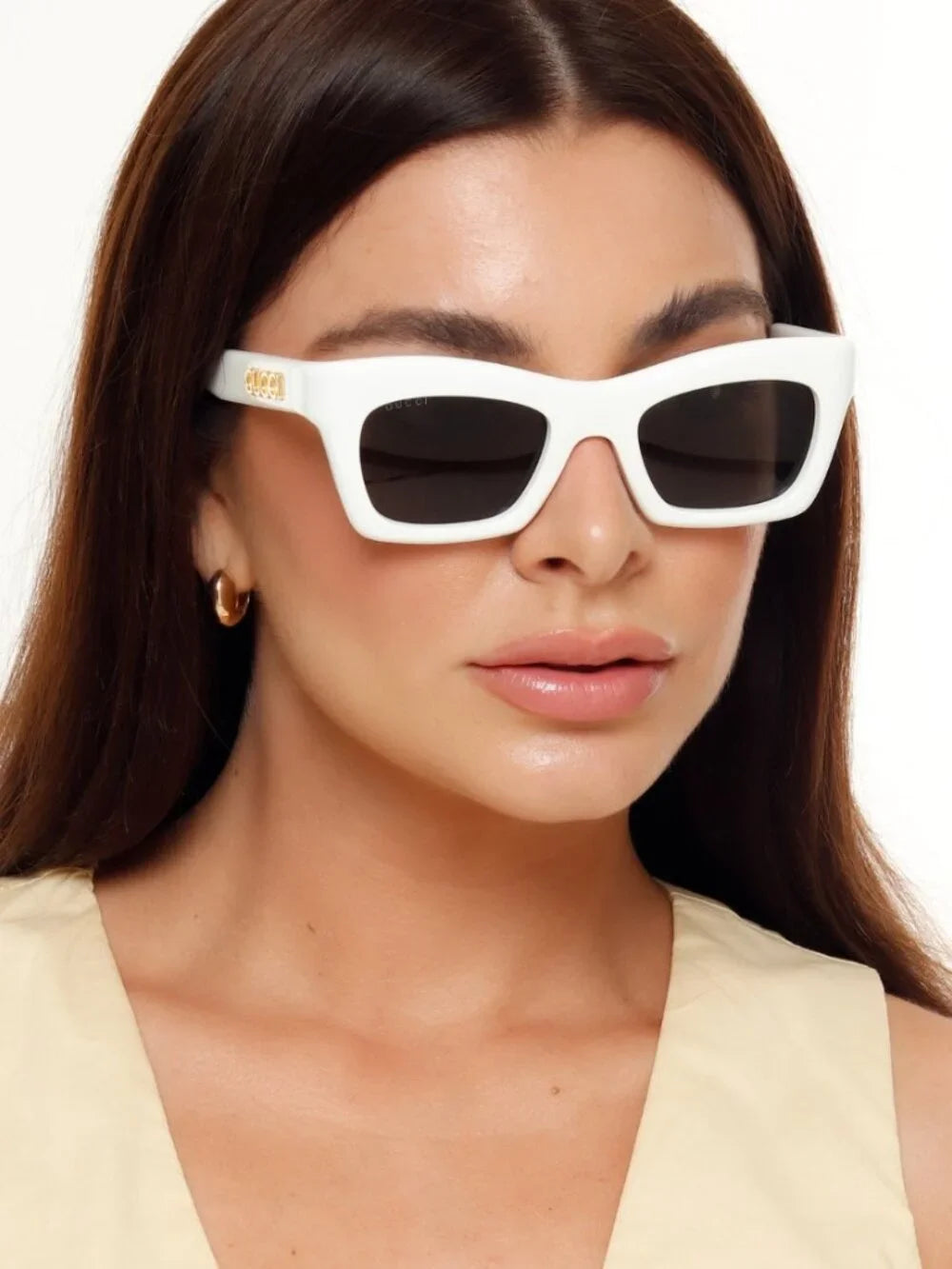 Woman wearing stylish white rectangular luxury sunglasses with dark lenses.