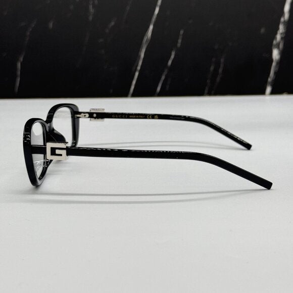 Black luxury designer eyeglasses with gold metal accents on a white surface.